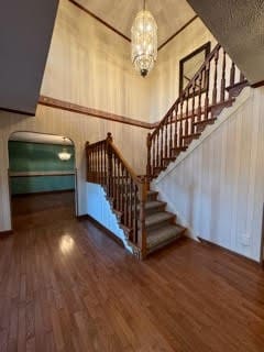 staircase featuring dark hardwood / wood-style flooring, an inviting chandelier, and a high ceiling