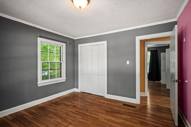 unfurnished bedroom with dark wood-type flooring, ornamental molding, a closet, and a textured ceiling