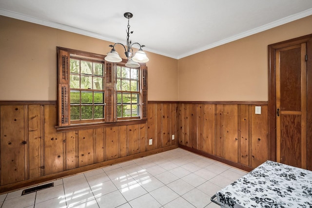 unfurnished dining area with crown molding, wood walls, a chandelier, and light tile patterned floors