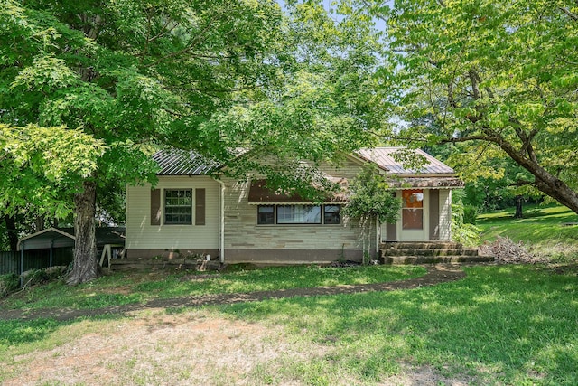 view of property hidden behind natural elements featuring a front yard and a carport