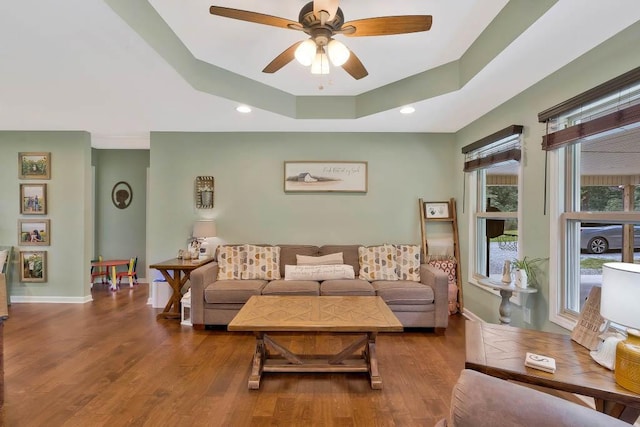 living room featuring ceiling fan, a raised ceiling, and hardwood / wood-style floors