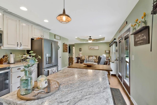 kitchen with ceiling fan, appliances with stainless steel finishes, pendant lighting, and light stone counters