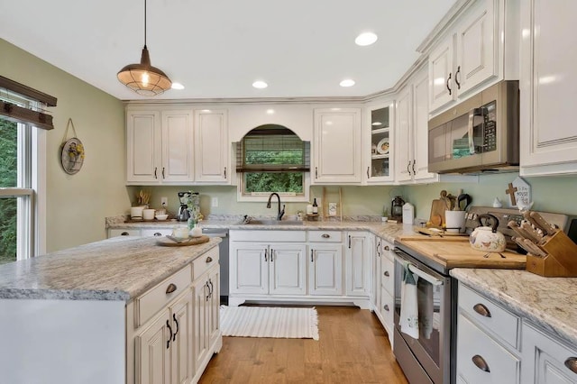 kitchen featuring white cabinetry, appliances with stainless steel finishes, sink, and hanging light fixtures