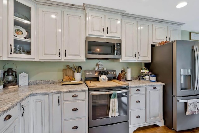 kitchen with light stone counters, stainless steel appliances, and white cabinets