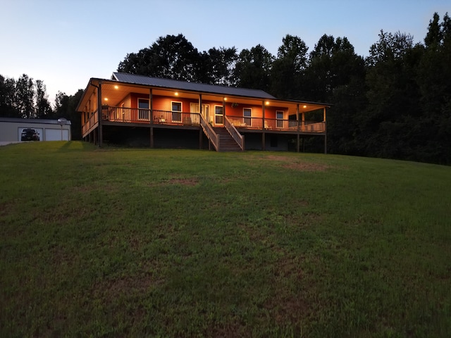 back house at dusk with a wooden deck and a lawn