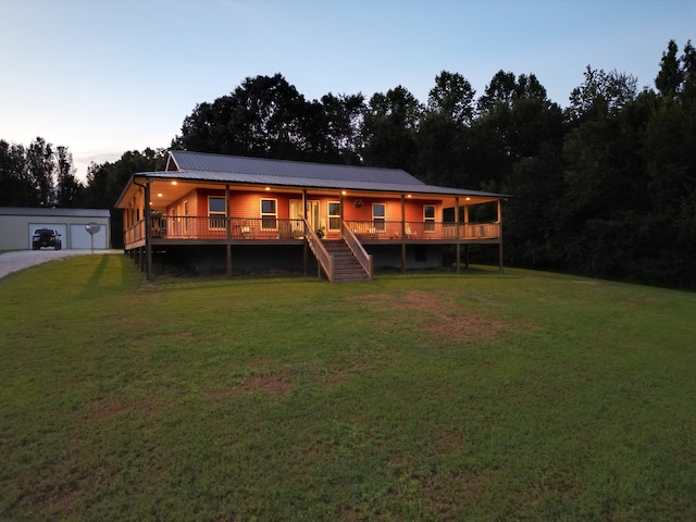 back house at dusk with a lawn and a deck