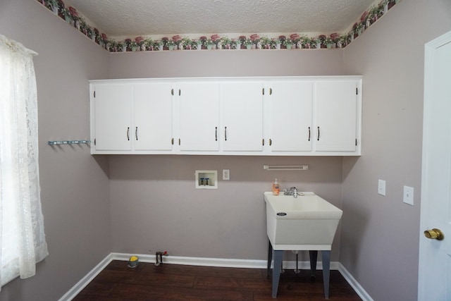 laundry room with hookup for a washing machine, dark wood-type flooring, cabinets, and a textured ceiling