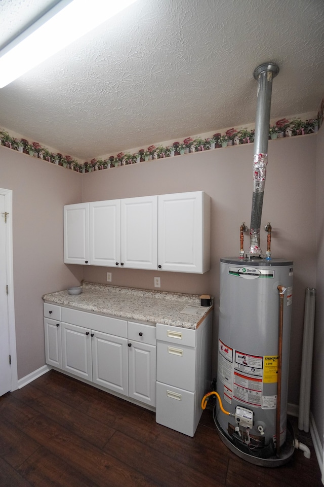 interior space featuring water heater, white cabinetry, light stone counters, dark wood-type flooring, and a textured ceiling