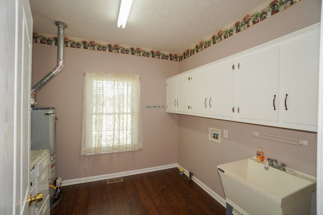 clothes washing area with sink, cabinets, a textured ceiling, dark hardwood / wood-style floors, and water heater