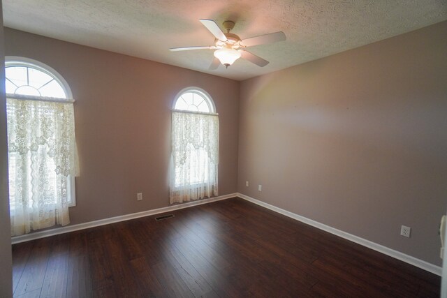 spare room featuring dark wood-type flooring, ceiling fan, and a textured ceiling