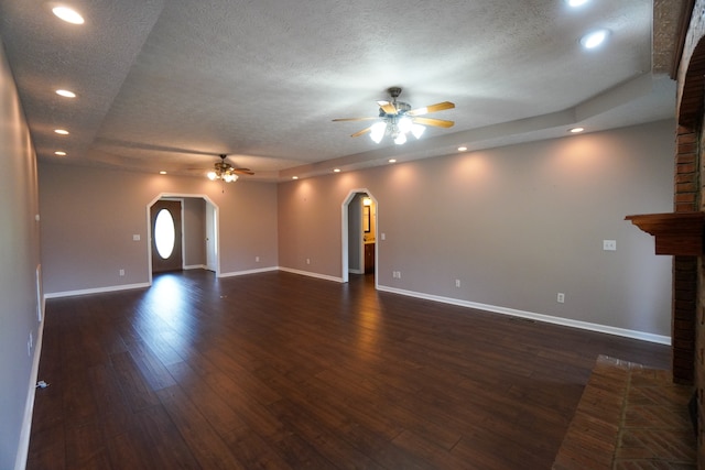 unfurnished living room featuring a fireplace, dark wood-type flooring, a textured ceiling, and ceiling fan