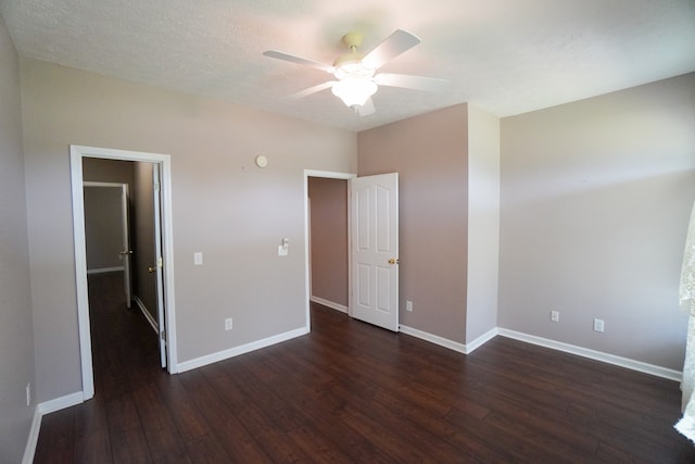 unfurnished bedroom with a textured ceiling, dark wood-type flooring, and ceiling fan