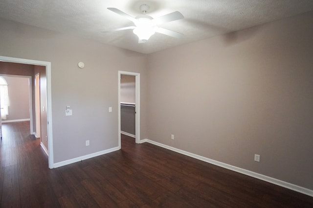 unfurnished bedroom featuring a walk in closet, a textured ceiling, dark hardwood / wood-style flooring, a closet, and ceiling fan