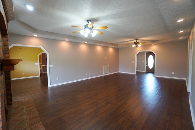 unfurnished living room featuring dark wood-type flooring, a textured ceiling, ceiling fan, and a fireplace