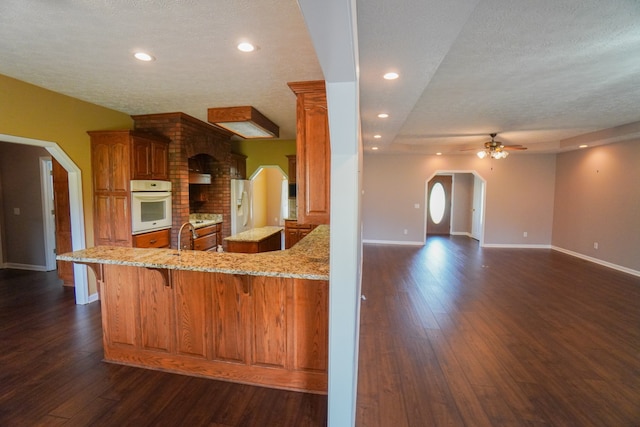 kitchen featuring white appliances, a breakfast bar, kitchen peninsula, and dark hardwood / wood-style flooring