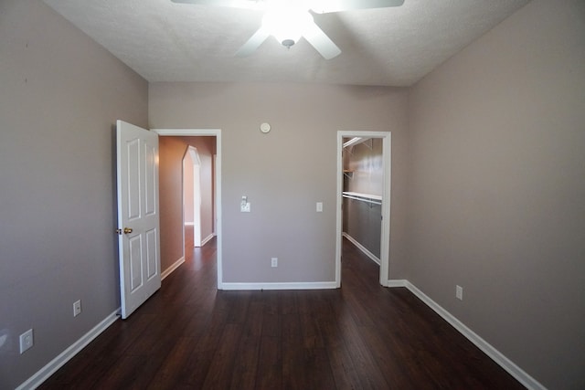 unfurnished bedroom featuring a closet, dark hardwood / wood-style floors, ceiling fan, and a spacious closet