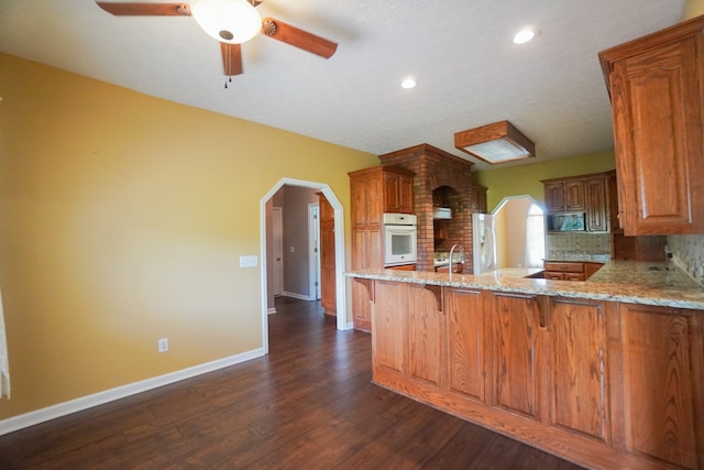 kitchen featuring tasteful backsplash, sink, oven, dark hardwood / wood-style flooring, and kitchen peninsula