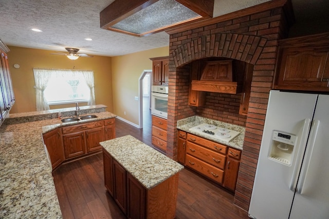 kitchen featuring sink, custom exhaust hood, white appliances, dark wood-type flooring, and a textured ceiling