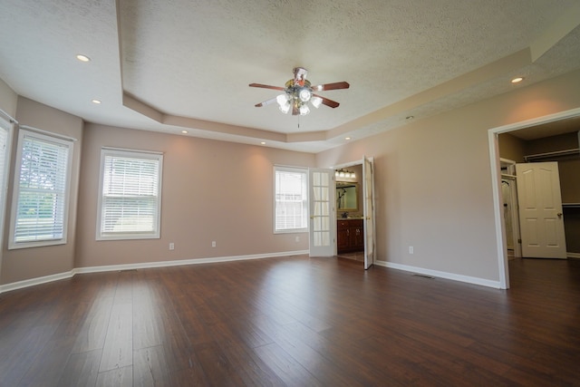 unfurnished room with a tray ceiling, dark hardwood / wood-style floors, and a textured ceiling