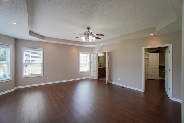 spare room featuring ceiling fan, dark hardwood / wood-style floors, a raised ceiling, and a textured ceiling