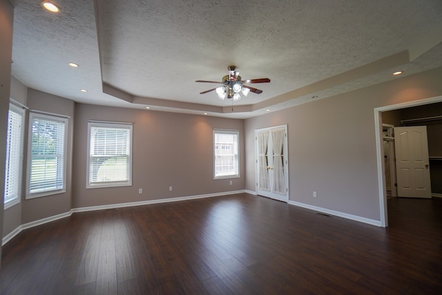 unfurnished room featuring ceiling fan, dark hardwood / wood-style floors, a textured ceiling, and a tray ceiling