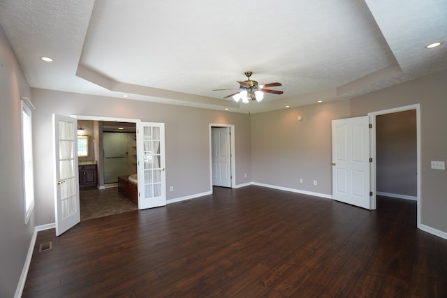 empty room with french doors, a textured ceiling, dark hardwood / wood-style floors, a raised ceiling, and ceiling fan