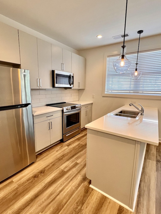 kitchen featuring decorative light fixtures, visible vents, light countertops, appliances with stainless steel finishes, and a sink