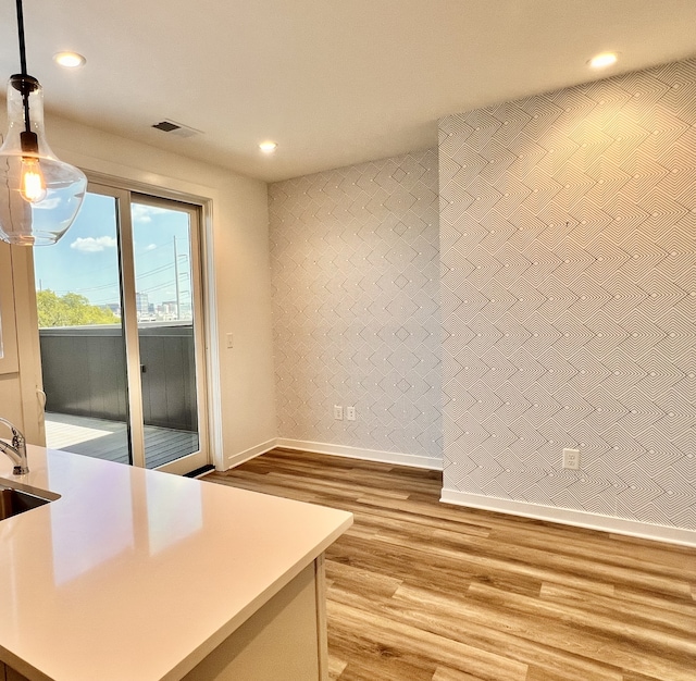 interior space with light hardwood / wood-style flooring, sink, and pendant lighting