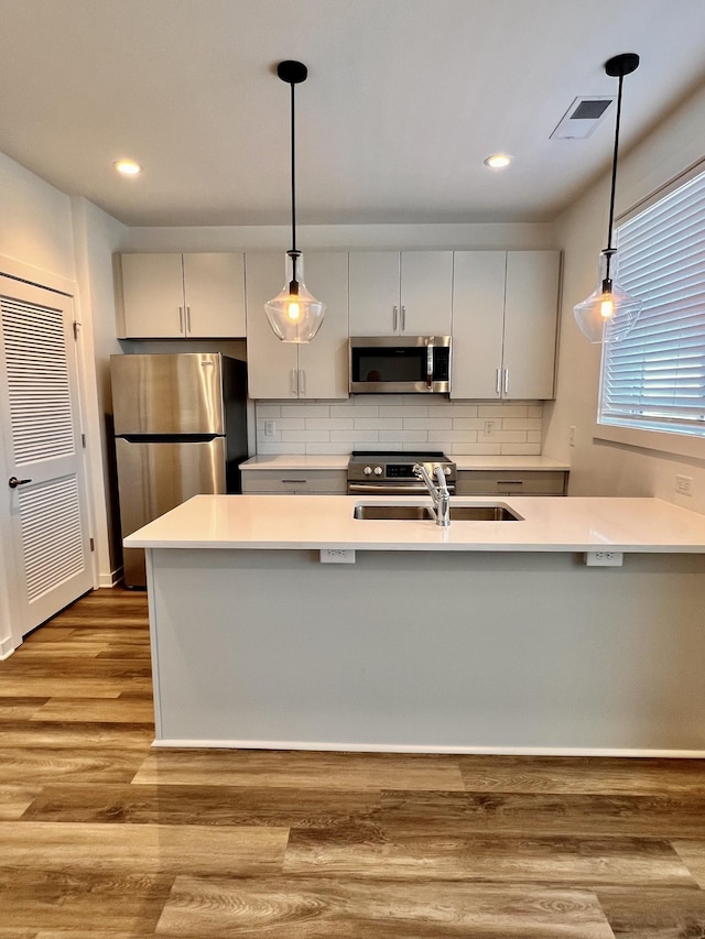 kitchen with hanging light fixtures, visible vents, stainless steel appliances, and light countertops