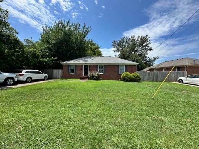 single story home featuring fence and a front lawn