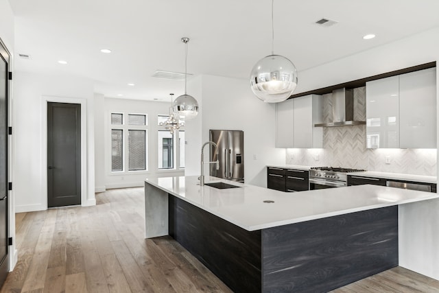 kitchen featuring appliances with stainless steel finishes, backsplash, white cabinets, sink, and wall chimney exhaust hood