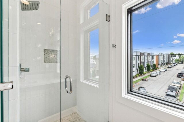 bathroom featuring a shower with shower door and plenty of natural light