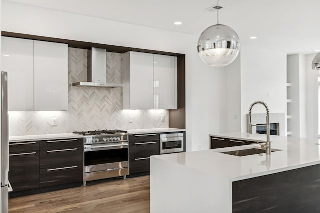 kitchen featuring stainless steel appliances, white cabinets, hardwood / wood-style floors, backsplash, and wall chimney exhaust hood