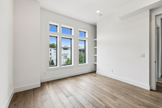 empty room featuring light wood-type flooring and built in features