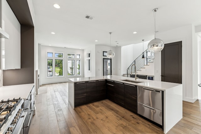 kitchen featuring dark brown cabinets, light hardwood / wood-style flooring, sink, and hanging light fixtures