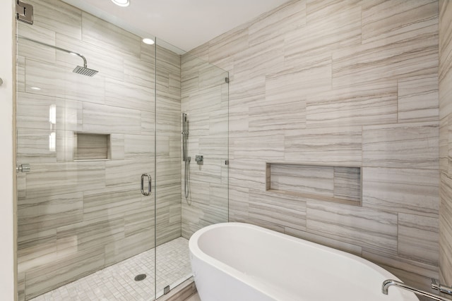 bathroom featuring tile walls and independent shower and bath