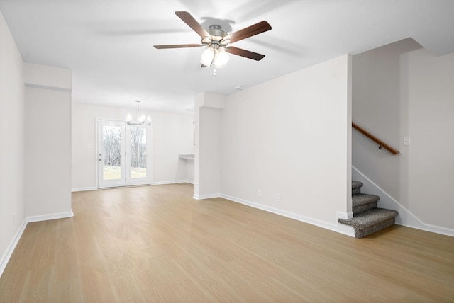 unfurnished living room featuring ceiling fan with notable chandelier and light hardwood / wood-style flooring