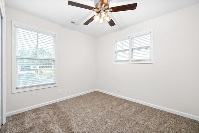 empty room featuring a healthy amount of sunlight, carpet, and ceiling fan