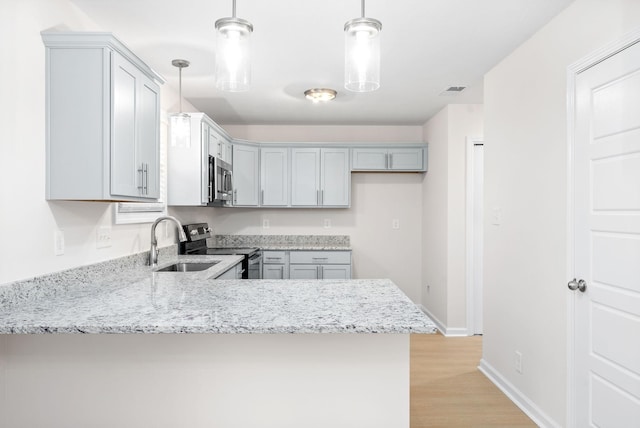 kitchen featuring appliances with stainless steel finishes, hanging light fixtures, gray cabinetry, sink, and kitchen peninsula