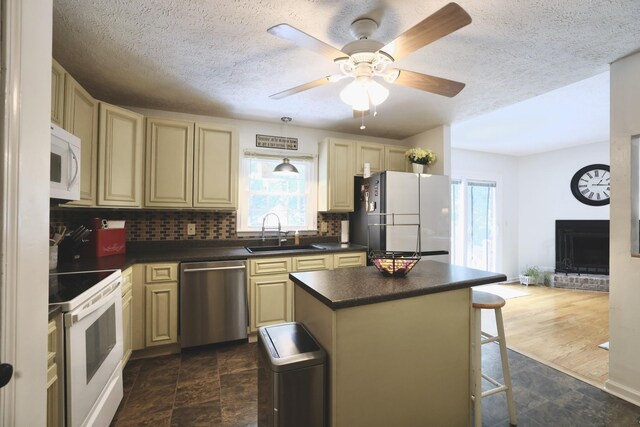 kitchen featuring white appliances, cream cabinetry, backsplash, dark tile patterned floors, and sink