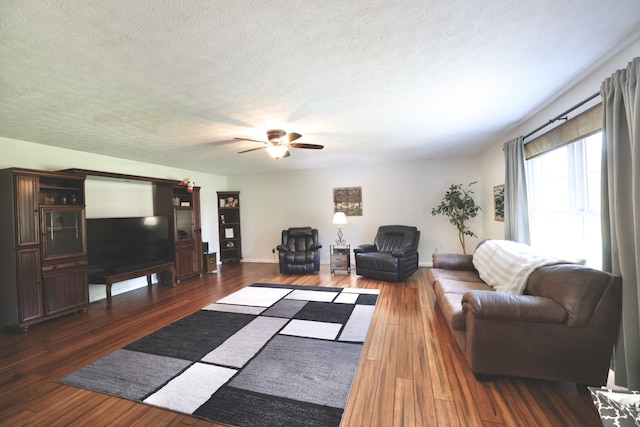 living room featuring ceiling fan, dark hardwood / wood-style flooring, and a textured ceiling