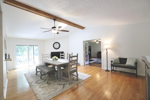 dining area featuring a textured ceiling, lofted ceiling with beams, light wood-type flooring, and ceiling fan