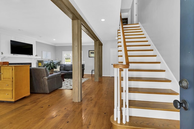 stairway with crown molding and wood-type flooring