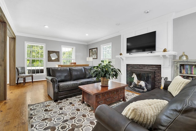 living room featuring crown molding, light wood-type flooring, and a brick fireplace