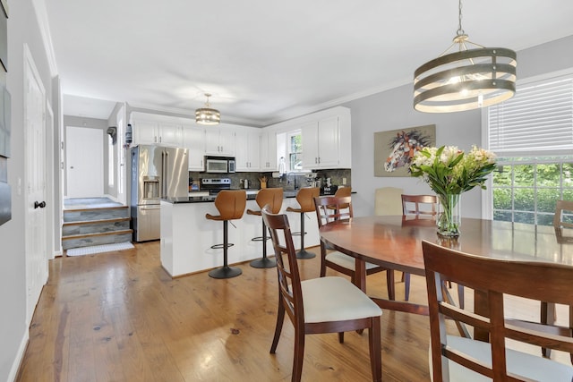 dining area featuring light hardwood / wood-style flooring, a healthy amount of sunlight, and ornamental molding