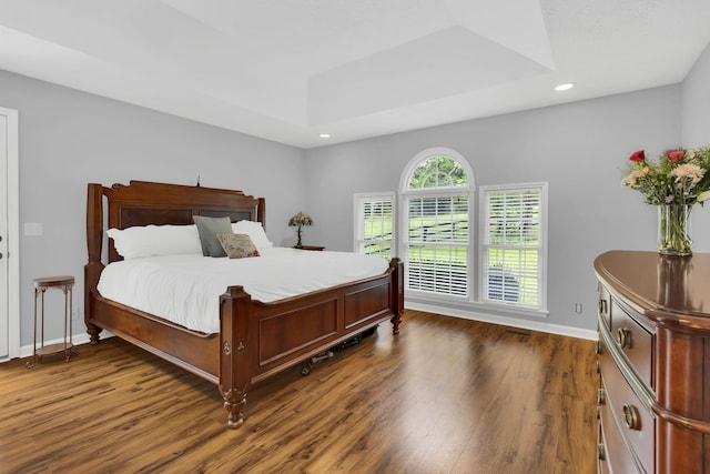 bedroom featuring dark hardwood / wood-style floors and a tray ceiling