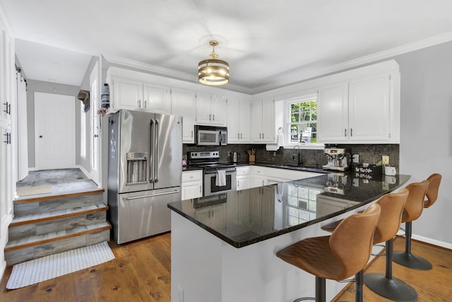 kitchen with dark hardwood / wood-style floors, tasteful backsplash, white cabinetry, kitchen peninsula, and stainless steel appliances