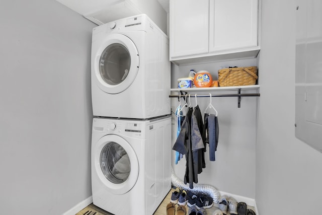 laundry area with stacked washer and clothes dryer and cabinets