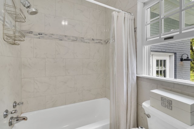 bathroom featuring toilet, shower / bathtub combination with curtain, and tile walls