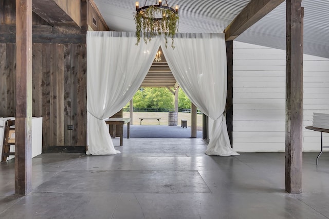 interior space featuring vaulted ceiling, wood walls, and a chandelier